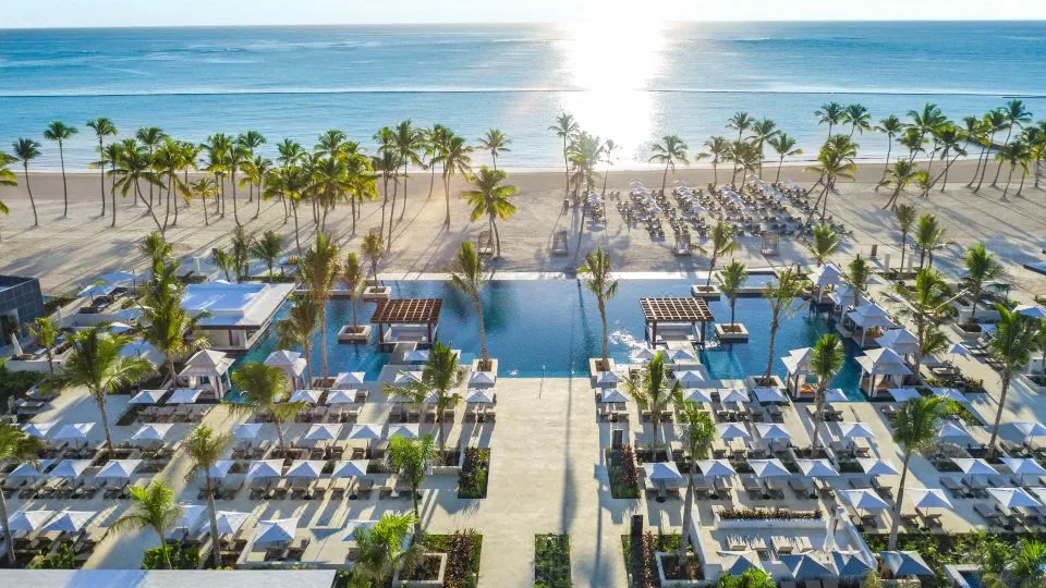 Vista real do Hyatt Zilara Cap Cana, com piscina, palmeiras e praia ao fundo.