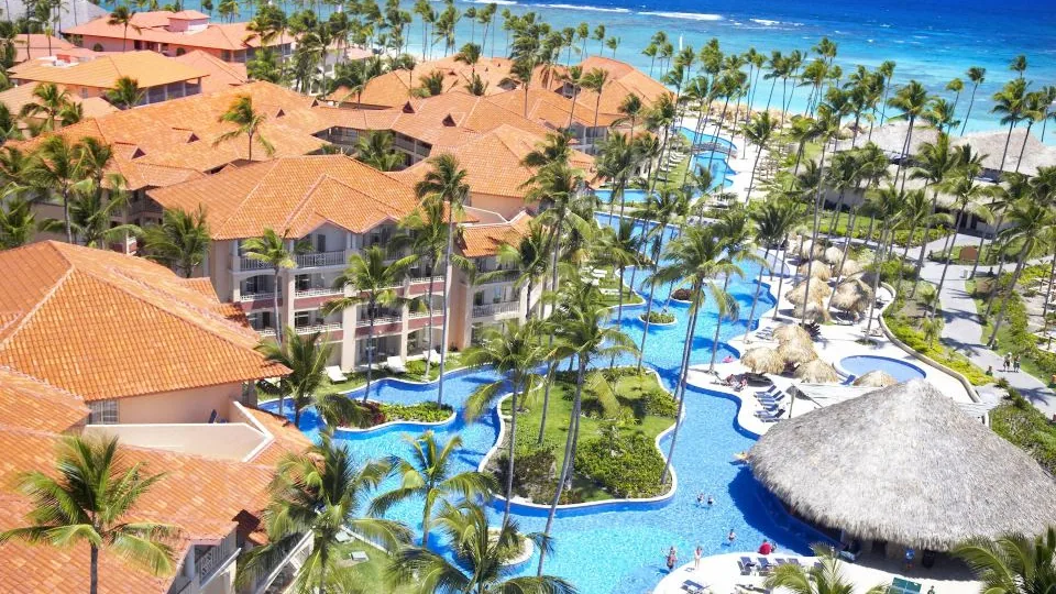 Vista real do Majestic Elegance Punta Cana, com piscinas e edifícios junto a palmeiras.