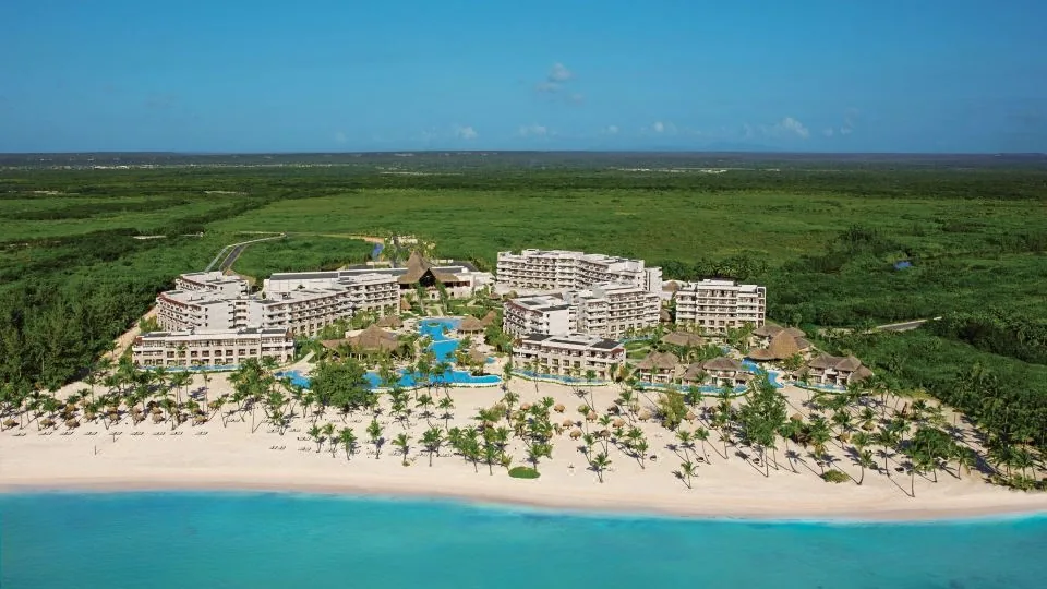 Vista real do Secrets Cap Cana Resort & Spa junto à praia e vegetação tropical.